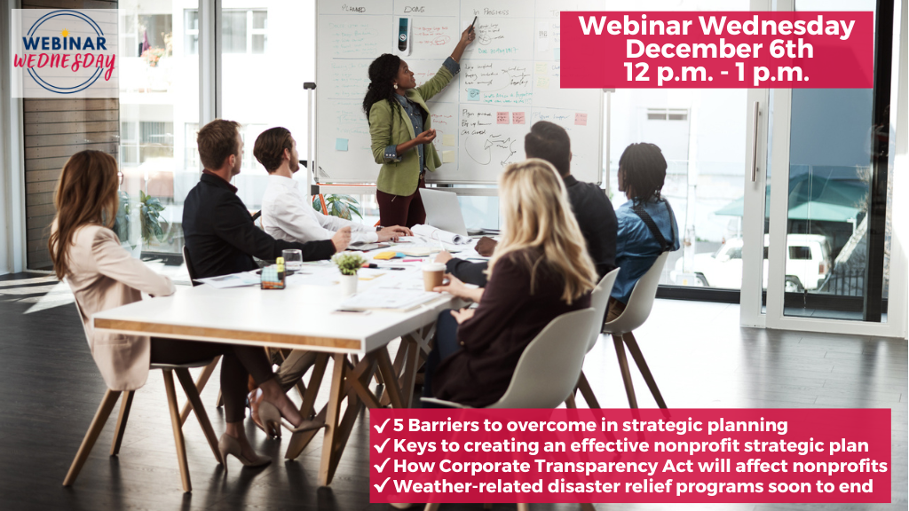 A multi-ethnic group of nonprofit employees are in a strategic planning session with six at the table and an African American woman leading the session